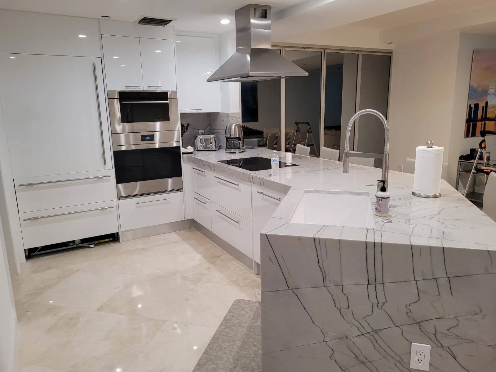 White gloss kitchen with waterfall quartz island and hood