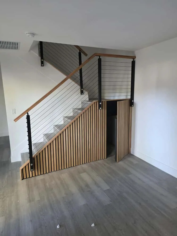Modern staircase with wood slat wainscot and cable railing